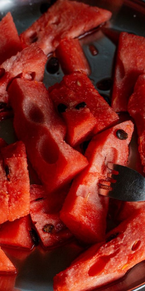 Juicy watermelon slices with seeds on a stainless steel plate and a fork. Best Restaurant in Kubwa Abuja